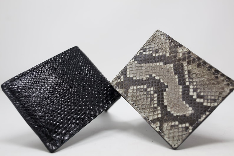 Peut inclure: Deux porte-cartes en cuir, l'un noir et l'autre &agrave; motif peau de serpent.
