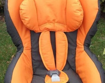 May include: A black and orange car seat with a headrest and a five-point harness.
