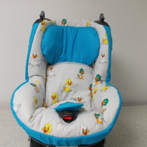 Puede incluir: Una funda para asiento de coche para bebé gris y azul con un patrón de patos. La funda tiene un reposacabezas azul y una base gris con un ribete azul.