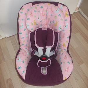 Puede incluir: Una funda de asiento de coche de color morado con un estampado de llama rosa y verde. La funda tiene un arnés de cinco puntos y un reposacabezas.