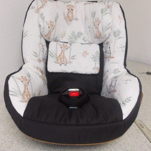Puede incluir: Silla de coche para bebé con base negra e interior estampado blanco. El estampado presenta jirafas, monos y follaje. El asiento tiene un arnés de seguridad negro y un botón de liberación rojo. Diseñado para la comodidad y la seguridad.