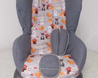 May include: A gray car seat cover with a white polka dot pattern. The cover features a colorful print of dogs and dog houses. The cover has a gray padded insert for added comfort.