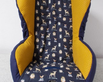 May include: A yellow and navy blue car seat cover with a woodland animal print featuring owls, deer, and hedgehogs. The cover has a strap for securing the seat belt.