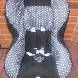 以下が含まれることがあります： グレーと白の星柄の黒いカーシート。シートにはヘッドレストと5点式ハーネスが付いています。