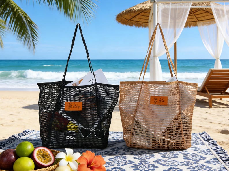 K&ouml;nnte beinhalten: Zwei Netztaschen, eine schwarze und eine beige, liegen auf einem Strandtuch. Die schwarze Tasche hat schwarze Henkel und ein kleines Lederetikett mit "Lily". Die beige Tasche hat beige Henkel. Beide Taschen sind mit Gegenst&auml;nden gef&uuml;llt.