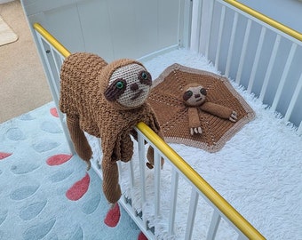 May include: A brown crocheted sloth toy with green eyes, hanging over the side of a white crib. A smaller brown crocheted sloth toy is lying on a white blanket inside the crib.