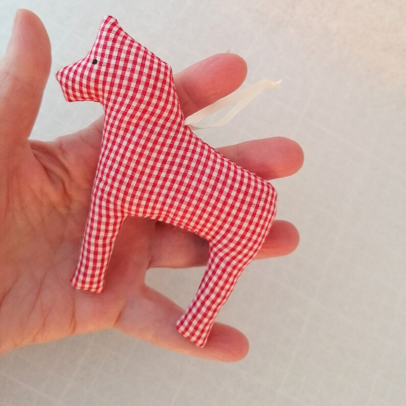 May include: Red and white gingham fabric horse ornament with a white ribbon loop for hanging.