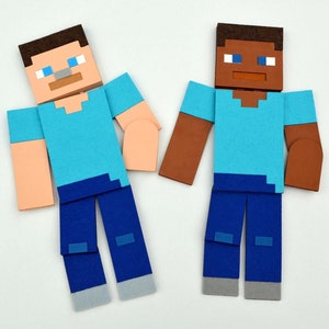 Könnte beinhalten: Zwei Papierfiguren von Minecraft-Charakteren. Eine Figur ist braun mit blauer Hose und einem hellblauen Hemd. Die andere Figur ist hellhäutig mit blauer Hose und einem hellblauen Hemd.