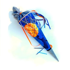 Könnte beinhalten: Eine blaue und graue Schultüte mit Basketball-Motiv. Die Tüte zeigt ein Basketballnetz, einen orangefarbenen Basketball und eine Silhouette eines Basketballspielers. Der Text "VITO" ist auf der Tüte zu sehen. Orange und blaue Bänder sind angebracht.