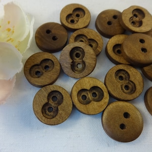 Könnte beinhalten: Eine Sammlung brauner Holzknöpfe mit jeweils zwei Löchern. Die Knöpfe sind rund und haben eine glatte Oberfläche.
