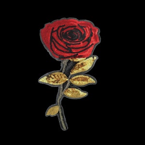 Könnte beinhalten: Eine rote Rose mit goldenen Paillettenblättern. Die Rose ist aus Stoff und Pailletten gefertigt.