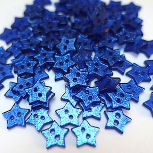 Könnte beinhalten: Ein Haufen blauer sternförmiger Knöpfe mit glitzernder Oberfläche.