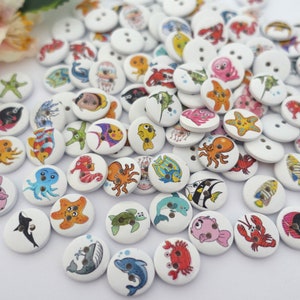 Peut inclure: Assortiment de boutons en bois colorés représentant différentes créatures marines, notamment des poissons, des étoiles de mer, des hippocampes et des pieuvres. Les boutons sont blancs et comportent deux trous chacun.