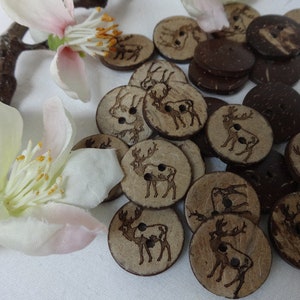 May include: A collection of brown coconut shell buttons with a deer design. The buttons are arranged in a pile on a white surface.