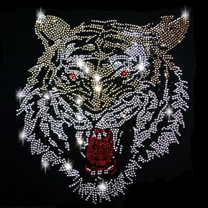 Könnte beinhalten: Ein weißes Tigerkopf-Design aus Strasssteinen auf schwarzem Hintergrund. Die Augen des Tigers sind rot und der Mund ist offen, wobei rote Zähne zu sehen sind.