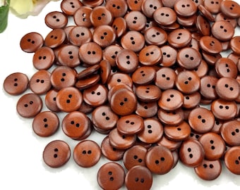 May include: A large pile of brown wooden buttons with two holes each. The buttons are all the same size and shape.