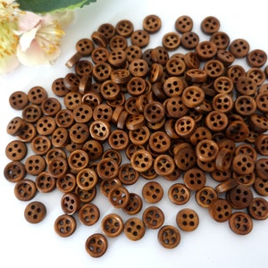 May include: A large pile of brown wooden buttons with four holes each. The buttons are arranged in a random pattern and are all the same size.