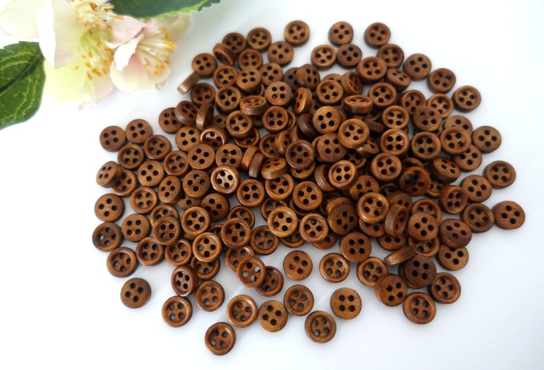 May include: A large pile of brown wooden buttons with four holes each. The buttons are arranged in a random pattern and are all the same size.