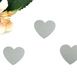 Può includere: Tre forme di cuore in feltro grigio su uno sfondo bianco.