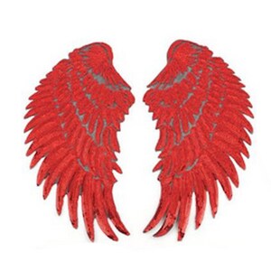 Könnte beinhalten: Ein Paar rote Pailletten-Engelsflügel mit einem detaillierten Design. Die Flügel sind aus Stoff und haben eine glitzernde Oberfläche.