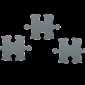 May include: Three grey jigsaw pieces, each with a unique shape, are arranged in a triangular formation against a black background.