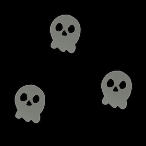 Könnte beinhalten: Drei graue Totenkopf-Halloween-Dekorationen auf schwarzem Hintergrund.