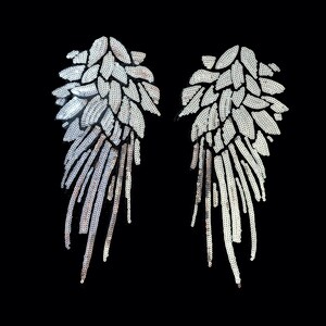 Puede incluir: Dos alas de ángel de lentejuelas plateadas sobre un fondo negro. Las alas están hechas de pequeñas lentejuelas brillantes y tienen un aspecto delicado y femenino.