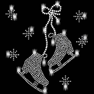 Puede incluir: Un par de patines de hielo blancos con un lazo en la parte superior, rodeados de copos de nieve brillantes. Los patines están hechos de diamantes de imitación y son perfectos para un proyecto de artesanía de temática invernal.