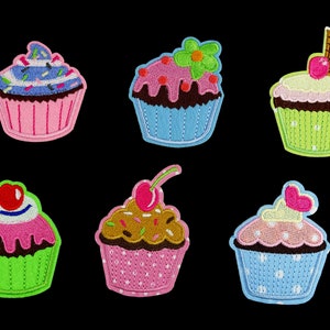 Könnte beinhalten: Sechs gestickte Cupcake-Patches in verschiedenen Farben und Designs. Die Cupcakes sind mit Streuseln, Kirschen, Zuckerguss und Blumen verziert.