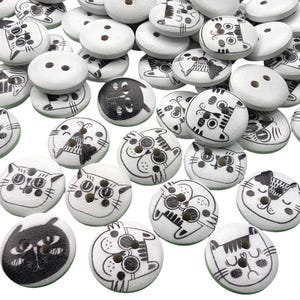 May include: A collection of white wooden buttons with black cat designs. The buttons are round and have two holes.