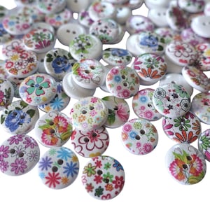 Peut inclure: Un ensemble de boutons en bois blanc avec des motifs floraux colorés. Les boutons sont ronds et ont deux trous.