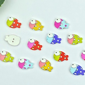 Könnte beinhalten: Sortiment von 12 Holz-Fischknöpfen in verschiedenen Farben, darunter Pink, Blau, Gelb, Grün und Rot. Jeder Knopf zeigt ein Cartoon-Fischdesign mit weißen Augen und schwarzen Pupillen. Die Knöpfe sind perfekt, um handwerklichen Arbeiten und Nähprojekten eine skurrile Note zu verleihen.