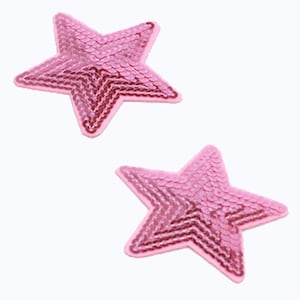 Könnte beinhalten: Zwei rosafarbene, glitzernde sternförmige Patches. Die Sterne bestehen aus Pailletten und haben einen rosafarbenen, schillernden Glanz.