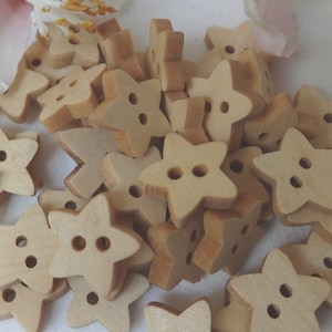 Könnte beinhalten: Ein Haufen hölzerner sternförmiger Knöpfe mit jeweils zwei Löchern. Die Knöpfe sind hellbraun.