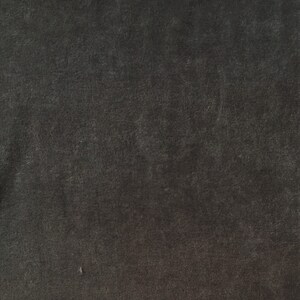 Puede incluir: Una tela texturizada gris oscuro con un brillo sutil. La tela tiene una superficie lisa y uniforme con un ligero grano.
