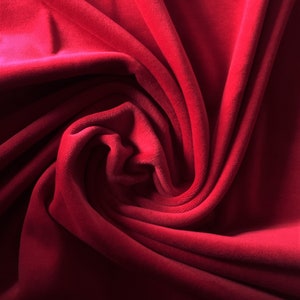 Könnte beinhalten: Nahaufnahme eines tief roten Samtstoffes, der die weiche Textur und die Falten des Materials zeigt.
