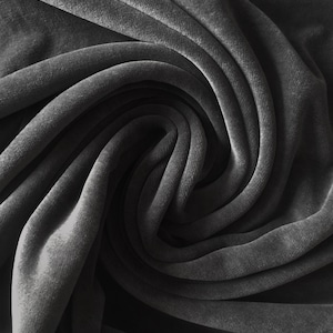 Puede incluir: Primer plano de una tela de terciopelo gris oscuro, que muestra la textura suave y los pliegues del material.