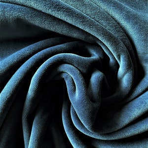 May include: Close-up of a soft, blue velvet fabric with a textured surface. The fabric is folded and draped, creating a luxurious and elegant look.
