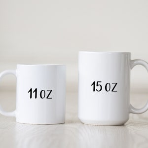 May include: Two white ceramic mugs with black text. The smaller mug is 11 oz and the larger mug is 15 oz.