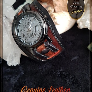 May include: A black leather watch band with a brown leather cuff. The watch face is silver with a skeleton design and black hands. The band has a black stitching detail. The text "Genuine Leather..." is visible at the bottom of the image. The text "Gifts And Charms Design" is visible in the upper right corner of the image.