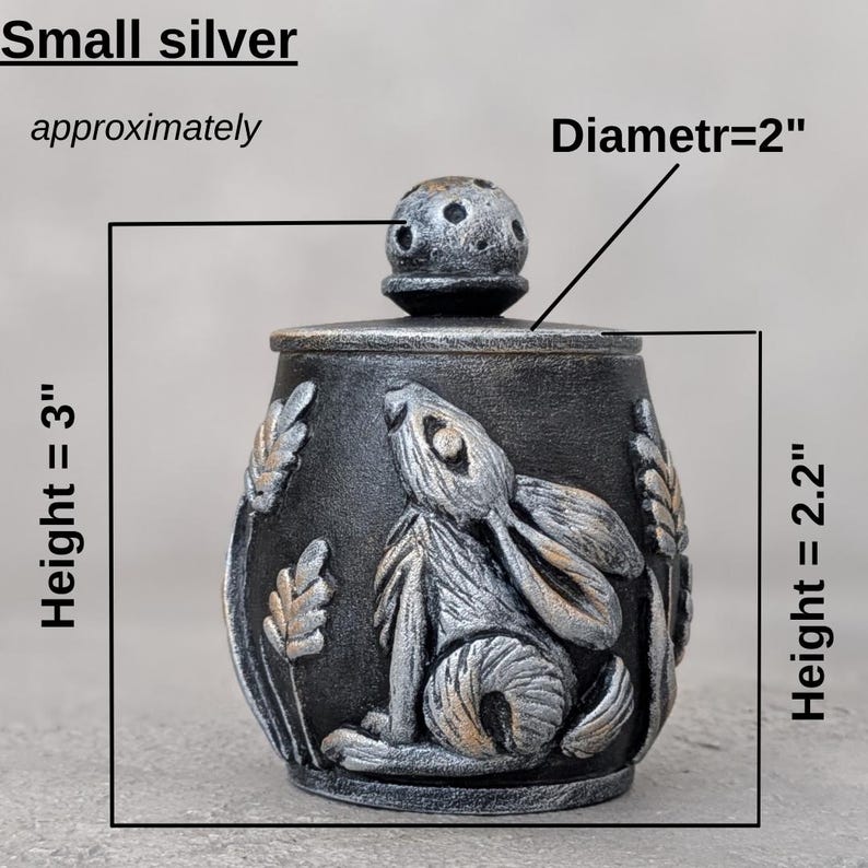 Puede incluir: Peque&ntilde;o tarro plateado con un dise&ntilde;o de conejo. El tarro mide aproximadamente 7,6 cm de alto y 5 cm de di&aacute;metro. El tarro tiene tapa y est&aacute; decorado con espigas de trigo.