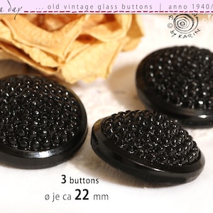 May include: Three vintage black glass buttons with a textured surface. The buttons are approximately 2.2 cm in diameter. The image includes text that reads "old vintage glass buttons | anno 1940/50/60".