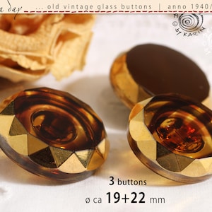 May include: Three vintage glass buttons with a faceted amber-coloured centre and a metallic gold-toned rim. The buttons feature a circular design with a central depression and a diameter of approximately 19 to 22 mm as indicated by the text.