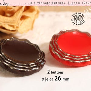 May include: Two vintage buttons, one dark brown and one red, with silver-coloured trim. The buttons are approximately 2.6 cm in diameter. The image includes text that reads "old vintage buttons" and "anno 1940/50/60".