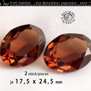 Può includere: Due pietre ovali in vetro sfaccettato di colore marrone, ciascuna misura 17,5 x 24,5 mm. Le pietre sono su una superficie bianca.