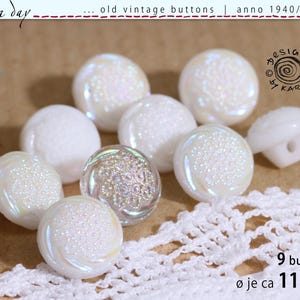 May include: A collection of nine round white buttons with an iridescent finish and a textured floral center pattern. Each button measures approximately 11 mm in diameter. The buttons feature a shank back for attachment and have a glossy surface.
