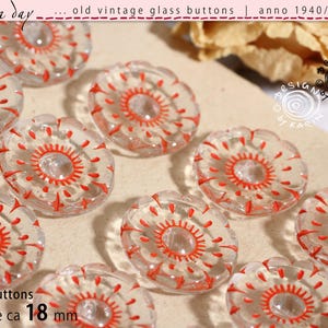 Op de afbeelding: Een verzameling doorzichtige glazen knopen met een cirkelvormig rood geschilderd patroon. Elke knoop heeft een geschulpte rand en een centraal gat. De tekst geeft aan dat er 24 knopen zijn, elk met een diameter van circa 18 mm.
