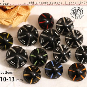 Peut inclure: Treize boutons ronds noirs avec des motifs gravés en forme d'étoile remplis de diverses couleurs, notamment jaune, rouge, blanc, vert, bleu et orange. Les boutons mesurent environ 10-13 mm de diamètre et présentent un design vintage.