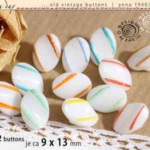 May include: A set of 12 vintage white oval buttons with diagonal stripes in various colours, including orange, red, blue, green, and yellow. Each button measures approximately 9 x 13 mm. The buttons are from the 1940s, 1950s, and 1960s.