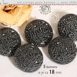 Op de afbeelding: Vijf vintage, donkergrijze glazen knopen met een getextureerd oppervlak. Elke knoop heeft een diameter van ongeveer 1,8 cm. De afbeelding bevat de tekst "old vintage glass buttons | anno 1940/50/60".